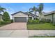 Inviting one-story home with a brick driveway, mature palm trees, and lush green lawn at 11050 Sandhill Preserve Dr, Sarasota, FL 34238