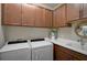 Functional laundry room with white washer and dryer, overhead cabinets and ample counter space at 11050 Sandhill Preserve Dr, Sarasota, FL 34238