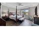 Serene main bedroom with a four-poster bed, bench, and picturesque lake view at 11050 Sandhill Preserve Dr, Sarasota, FL 34238