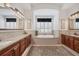 Bright bathroom featuring a soaking tub, dual vanities with granite counters, and decorative accents at 1137 N Lake Shore Dr, Sarasota, FL 34231