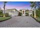 Stately home featuring a brick driveway, columned entry, three-car garage, tile roof, and lush tropical landscaping at 1137 N Lake Shore Dr, Sarasota, FL 34231