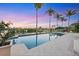 Stunning waterfront pool at dusk, framed by swaying palm trees and colorful skies, offering a peaceful retreat at 1137 N Lake Shore Dr, Sarasota, FL 34231