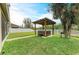 Backyard featuring a covered hot tub, lush lawn, and white fence at 11411 Flora Springs Dr, Riverview, FL 33579