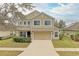 Two-story tan home with a two-car garage, well-manicured lawn, and established landscaping at 11411 Flora Springs Dr, Riverview, FL 33579