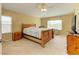 Well-lit main bedroom with a wooden bed frame, neutral walls and carpet, and a ceiling fan at 11411 Flora Springs Dr, Riverview, FL 33579