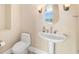 Powder room featuring a pedestal sink, toilet, neutral walls, and decorative lighting at 130 Riviera Dunes Way # 1201, Palmetto, FL 34221