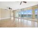 Living room with travertine flooring, ceiling fans, and sliding glass doors that open to the balcony at 130 Riviera Dunes Way # 1201, Palmetto, FL 34221