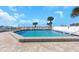 Community pool with crystal clear water, surrounded by lounge chairs and swaying palm trees at 1300 Gulf Blvd # 202, Indian Rocks Beach, FL 33785