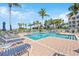 Community pool surrounded by lush tropical landscaping, lounge chairs, and palm trees at 14021 Bellagio Way # 309, Osprey, FL 34229