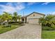 Charming single-story home features a paver driveway, two-car garage, and tropical landscaping under a blue sky at 17234 Blue Ridge Pl, Bradenton, FL 34211