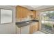 Compact kitchen featuring wood cabinets, light countertops, window with natural light, and essential appliances at 2 Antigua Cir # 4, Englewood, FL 34223