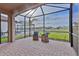 Relaxing screened patio with brick flooring and a view of the backyard, pool, and neighboring houses at 3008 Tolmino Ct, Lakewood Ranch, FL 34211
