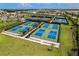 Aerial view of multiple pickleball courts featuring blue and green surfaces, surrounded by lush landscaping at 3008 Tolmino Ct, Lakewood Ranch, FL 34211