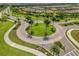 Aerial view of a beautifully landscaped roundabout, enhanced by palm trees and colorful flower beds in a lush community at 3008 Tolmino Ct, Lakewood Ranch, FL 34211