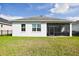 View of the back exterior of the house with a screened in patio and green lawn at 3711 Manorwood Loop, Parrish, FL 34219