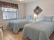 Cozy bedroom featuring two twin beds with blue quilted bedding and a window with blinds at 4440 47Th W Ave # 204, Bradenton, FL 34210