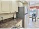 Galley kitchen featuring a stainless steel refrigerator, neutral countertops, and white cabinets with black hardware at 4440 47Th W Ave # 204, Bradenton, FL 34210