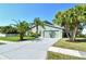 Home showcasing a well-maintained lawn, mature palm trees, and a long concrete driveway at 4712 Glenbrooke Dr, Sarasota, FL 34243
