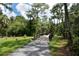 A charming wooden bridge spans a tranquil path surrounded by lush trees, creating a serene walking experience at 4712 Glenbrooke Dr, Sarasota, FL 34243
