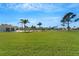 Expansive grassy backyard overlooking community pool, a pond, and swaying palm trees at 4811 Summertree Rd, Venice, FL 34293