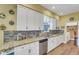 Bright kitchen featuring white cabinets, granite countertops, stainless steel appliances, and mosaic backsplash at 4811 Summertree Rd, Venice, FL 34293