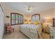 Sunny bedroom with a floral bedding, shuttered windows, and a ceiling fan at 6617 Nautical Dr, Lakewood Ranch, FL 34202
