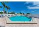 Community pool with clear blue water, surrounded by lounge chairs and lush tropical landscaping under a bright blue sky at 7490 Palm Island Dr # 2324, Placida, FL 33946