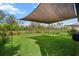 Beautiful backyard with lush green grass, black fence, and large shade sail at 8619 Firefly Pl, Parrish, FL 34219