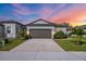 Charming single Gathering home with a well-manicured lawn, a two-car garage, and lovely landscaping at sunset at 8619 Firefly Pl, Parrish, FL 34219