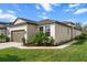 Single Gathering home featuring an attached garage, pristine lawn, and lush landscaping on a sunny day at 8619 Firefly Pl, Parrish, FL 34219