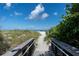 Path to the beach with dunes and plants on both sides, with the ocean and blue skies in the distance at 1604 Still River Dr, Venice, FL 34293