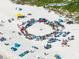 Aerial view of beach goers with beach chairs, umbrellas, and towels set up in a circle on white sands at 1604 Still River Dr, Venice, FL 34293