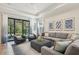 Spacious living room with a large sectional sofa, tray ceiling, and screened patio access at 1604 Still River Dr, Venice, FL 34293