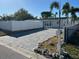 Charming home featuring a brick driveway, white fence, and lush palm trees under a clear blue sky at 2180 Orchid St, Sarasota, FL 34239