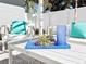 Outdoor seating area featuring white furniture, colorful pillows, and a blue glassware on a bright sunny day at 2180 Orchid St, Sarasota, FL 34239