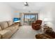 Cozy living room featuring neutral walls, patterned carpet, ceiling fan, and sliding glass doors to the lanai at 2395 Harbor Blvd # 322, Port Charlotte, FL 33952