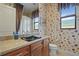 Bathroom with a dark bowl sink, stone countertops, and floral wallpaper at 2515 130Th E Ave, Parrish, FL 34219