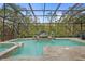 The custom pool with a sunbed features lush landscaping and a screen enclosure at 2515 130Th E Ave, Parrish, FL 34219