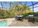 Screened-in outdoor dining area with a grill and view of the surrounding greenery at 2515 130Th E Ave, Parrish, FL 34219