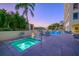 An evening view of a spa, lounge chairs, and a pool, all beautifully lit and surrounded by lush tropical landscaping at 35 Watergate Dr # 1101, Sarasota, FL 34236