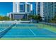 Well-maintained tennis courts with a vibrant blue surface, surrounded by lush greenery and modern buildings at 35 Watergate Dr # 1101, Sarasota, FL 34236
