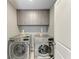 A laundry room featuring a front load washer and dryer with overhead cabinets for storage at 4411 Hearthstone Run, Palmetto, FL 34221