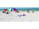 Scenic view of a sandy beach with colorful umbrellas, people relaxing, and clear blue ocean waters in the background at 462 Island Cir, Sarasota, FL 34242