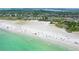 Aerial view of a crowded beach with turquoise water, white sand, and various colorful umbrellas dotting the shoreline at 462 Island Cir, Sarasota, FL 34242