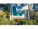 Aerial view of a private backyard pool with a spa, covered patio, and wooden dock, surrounded by lush greenery at 462 Island Cir, Sarasota, FL 34242