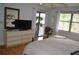 Light-filled bedroom featuring wood floors, a dresser with a TV, and access to a balcony at 4655 46Th Street W Ct # 201, Bradenton, FL 34210