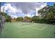 Well-maintained tennis court with green surface, surrounded by lush landscaping and trees at 4655 46Th Street W Ct # 201, Bradenton, FL 34210