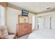 Well-lit main bedroom with a tray ceiling, TV, wooden dresser, and a relaxing sitting area at 5105 Pine Shadow Ln, North Port, FL 34287