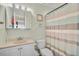 A well-lit bathroom features a vanity, toilet, mirror and a shower with a striped curtain at 5665 Midnight Pass Rd # 410, Sarasota, FL 34242