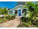 Charming exterior showcasing a quaint home with a blue door and beautiful landscaping with tropical trees at 635 Ohio Pl, Sarasota, FL 34236